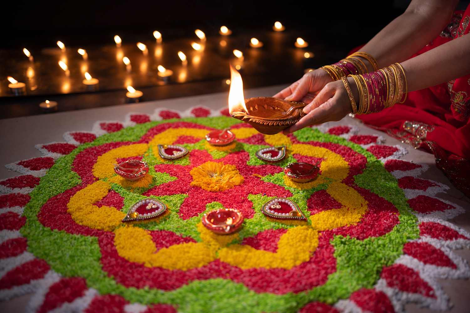 Clay oil lamps glow around a colorful rangoli during a festival of lights.