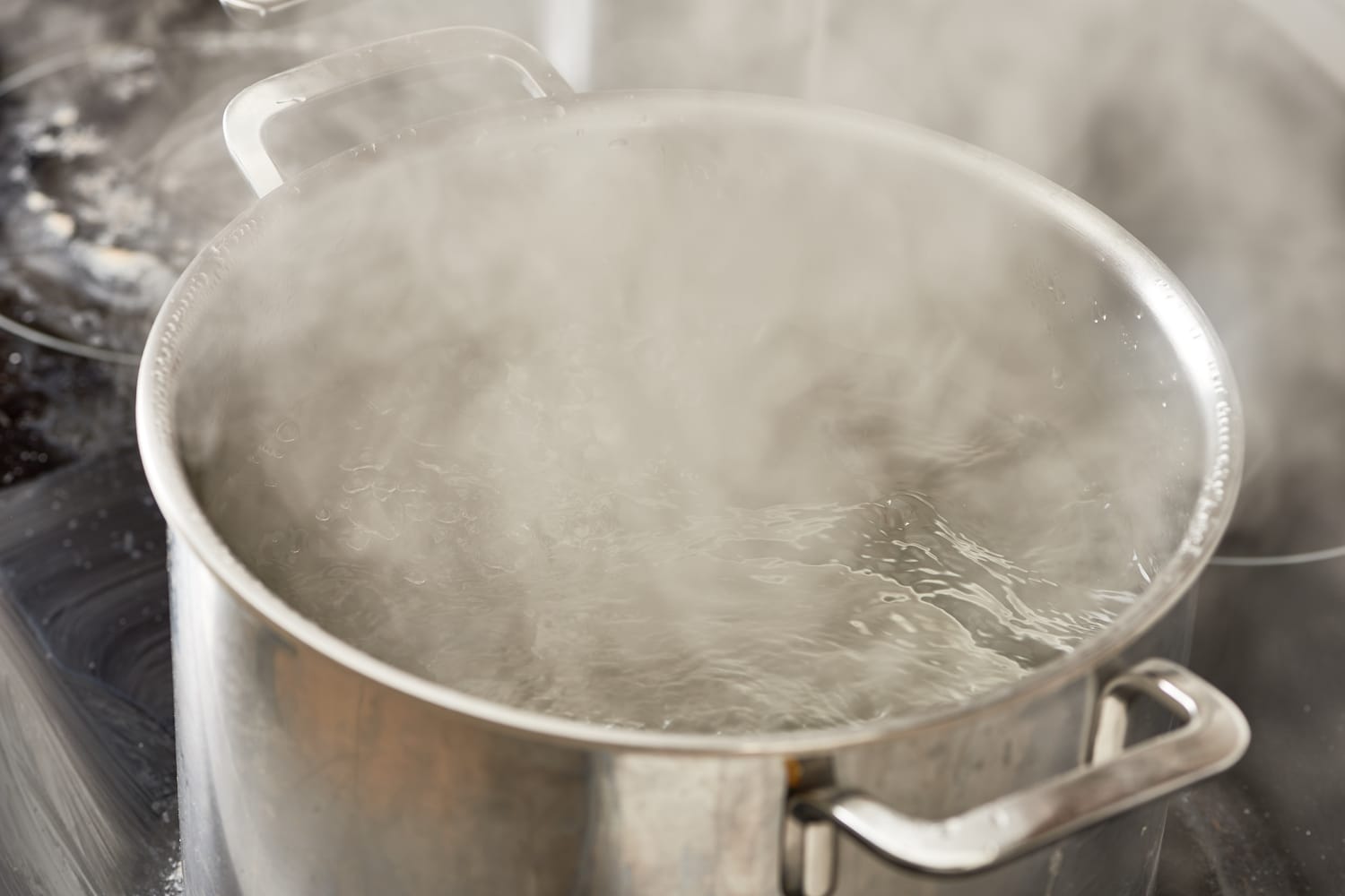 Boiling water in pan. Cooking pot on stove with water and steam