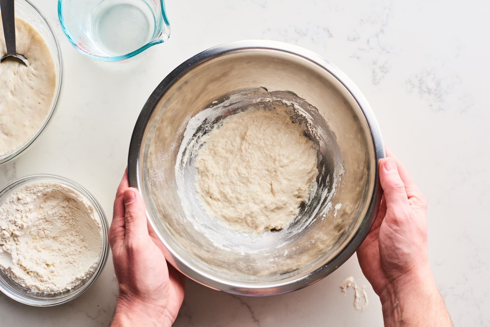 Making bread, mixing starter and yeasted water with flour