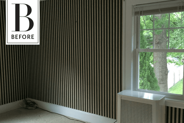 Empty room with black and white striped wallpaper, large window, and radiator cover.