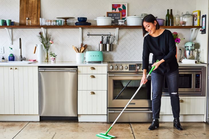 Woman cleans kitchen floor with Swiffer