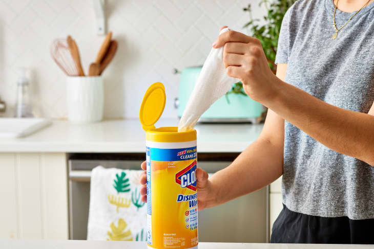 A woman in a kitchen pulling a disinfecting wipe out of its container