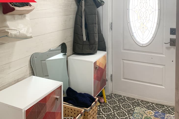 Before: entryway with baskets on the floor, low cabinets, and hanging hooks