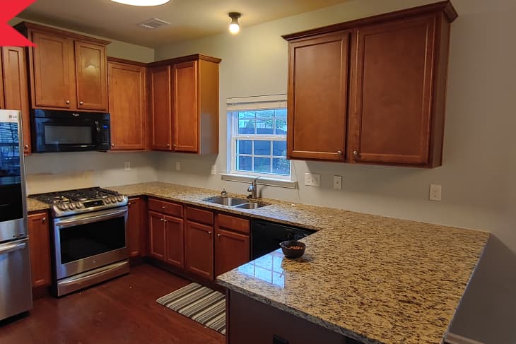 Before: Dated kitchen with dark wooden cabinets and floors and tan countertops