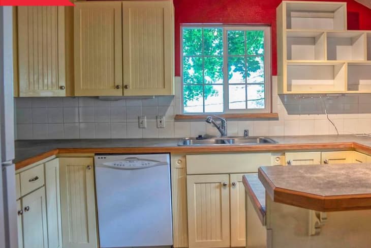 Before: Kitchen with red walls, pale yellow cabinets, and basic white square tile backsplash