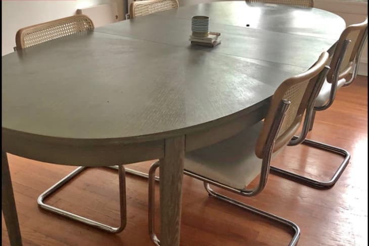 Before: Dining table with gray wood stain, surrounded by caned dining chairs