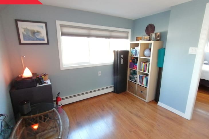 Before: Room with light blue walls and hardwood floors, furnished with a bookshelf and other assorted furniture