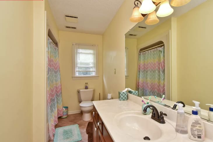 Before: Yellowish bathroom with rainbow shower curtain