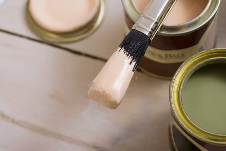 Small sample-sized containers of pink and green paint, with a brush resting on the pink can