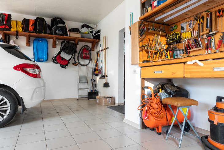 garage with wood shelving holding outdoor gear and a tool bench filled with tools