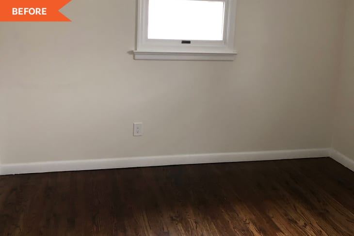 Empty room with dark hardwood floors, beige walls, and a small window.
