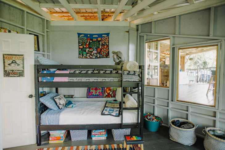 Bunk bed with colorful bedding, a wall tapestry, and toys in a cozy, light-filled room.