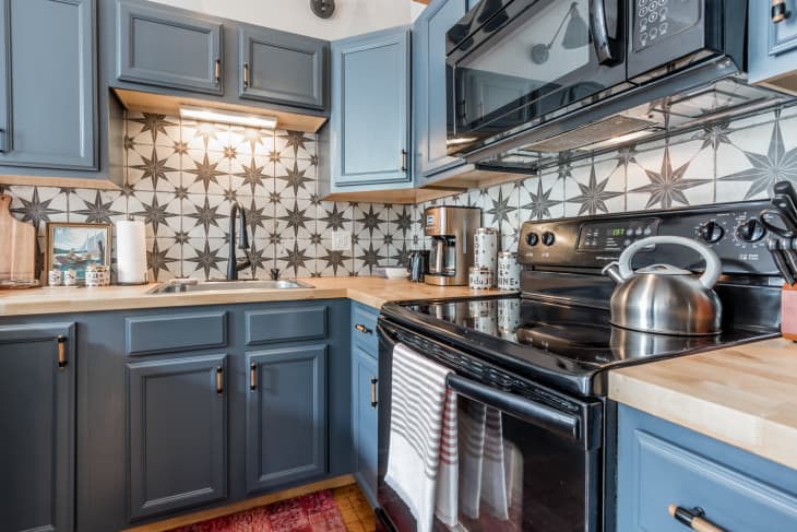 Ktichen with gray cabinets and black and white star-patterned backsplash