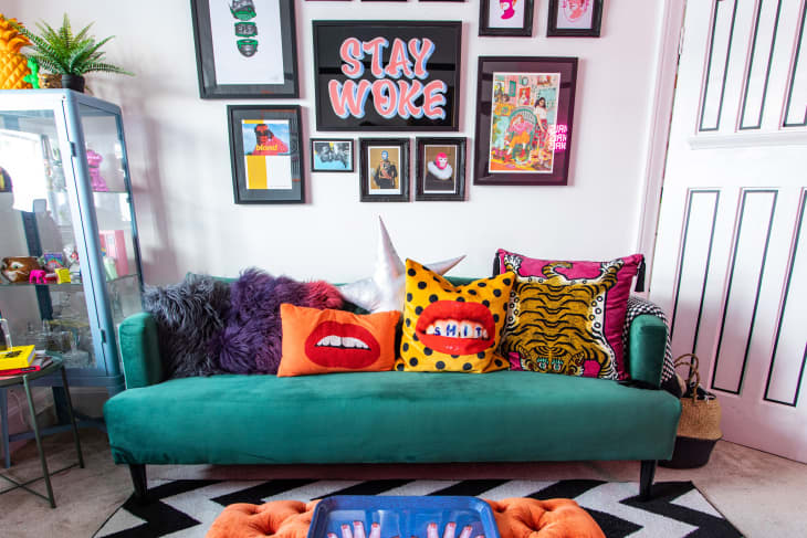 Colorful living room with green sofa, orange ottoman, chevron rug, and gallery wall behind sofa