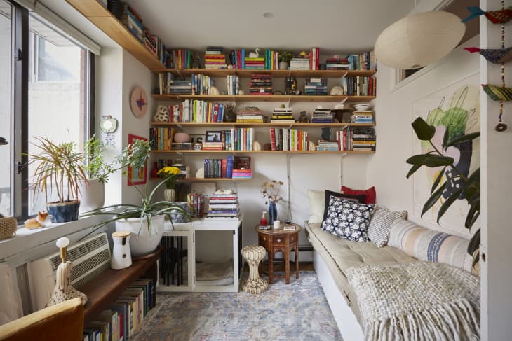 A room with bookshelves above and below the large window and along one wall.