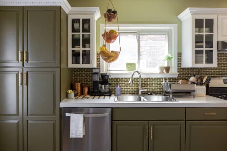 Light filled olive green kitchen with white countertops.