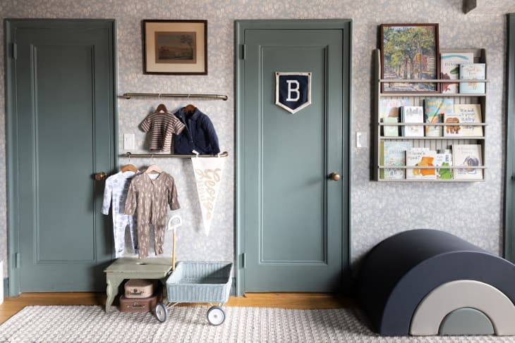 A kids room with wallpapered walls, grey-green ceilings and doors