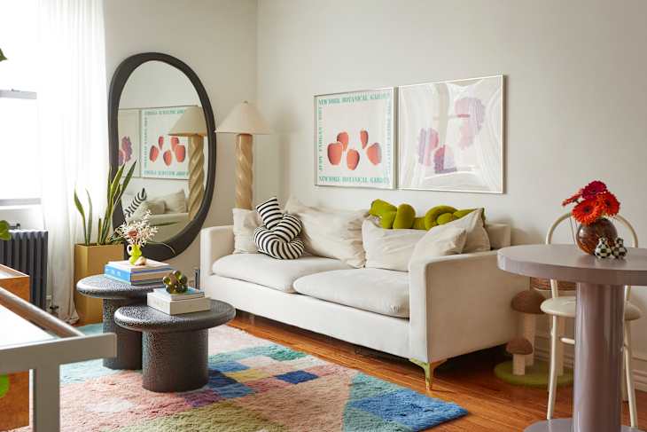 A white couch in a white living room with colorful artwork and a colorful rug