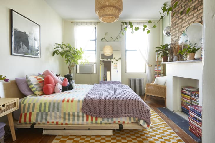 A small bedroom with books piled in the clean white fireplace