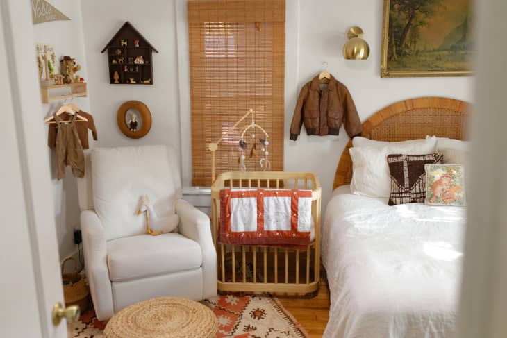 white bedroom with wood bassinet/crib and white armchair with lots of warm hued and natural fiber accents