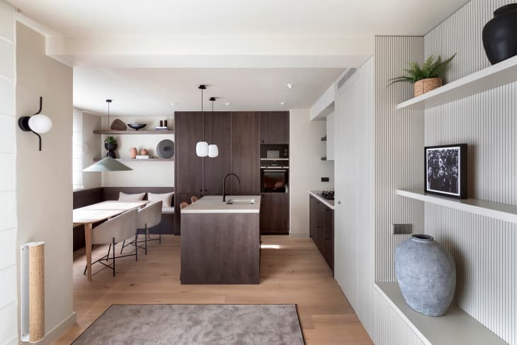 View into modern minimal white kitchen and dining room with dark brown kitchen island and cabinets