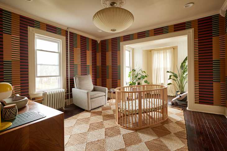 Baby crib in nursery with graphic wallpaper.