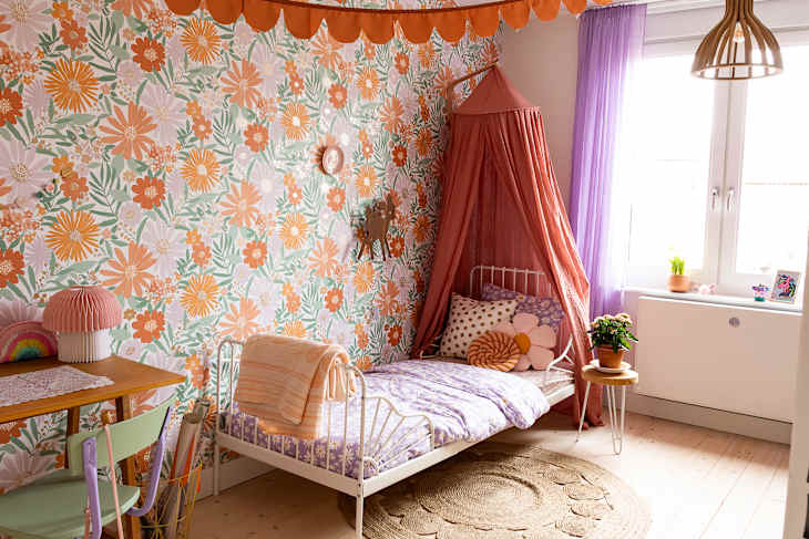 Bed place in corner of child's bedroom with floral wallpaper.