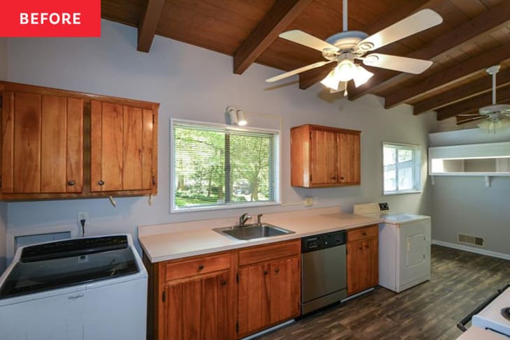 dark wood ceiling with beams, ceiling fan, wood cabinet kitchen with washing machine in kitchen before remodel
