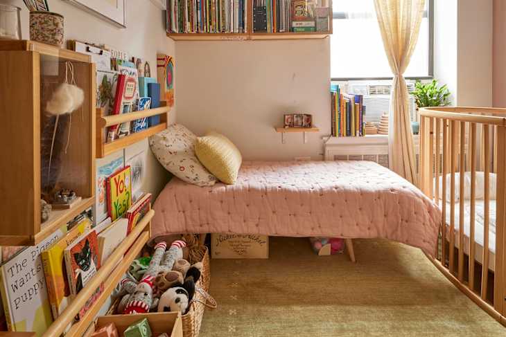 Pink comforter on neatly made child's bed.