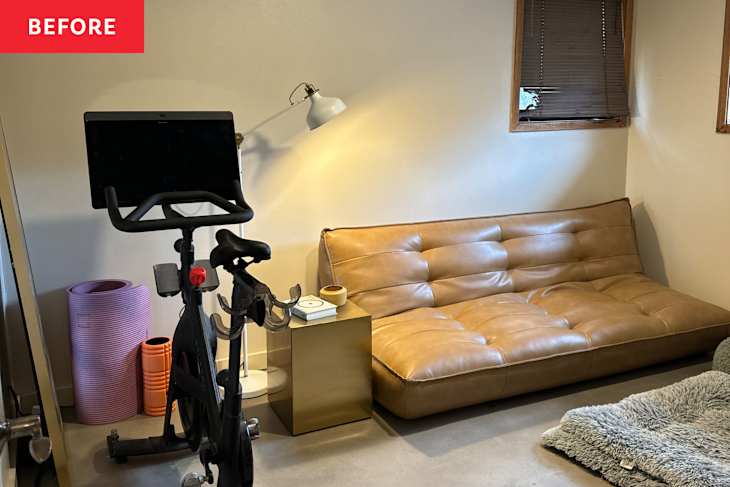 A home gym corner featuring a stationary bike, a brown leather sofa, a gold side table, and yoga mats.
