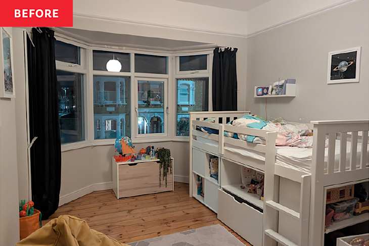 A cozy children's bedroom featuring a loft bed, wooden flooring, a toy storage box, and a large window with black curtains.