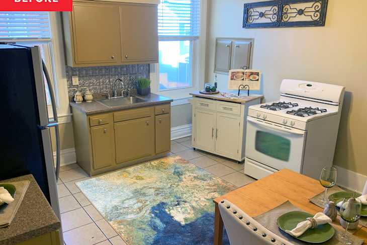 Kitchen with beige cabinets, stainless steel fridge, white stove, and a wooden dining table set for two with green plates.