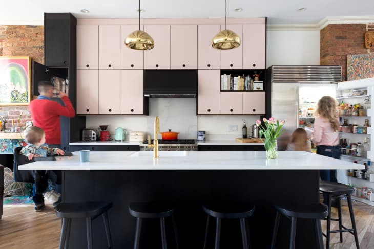 A family of four looking through the storage in a pink and black kitchen