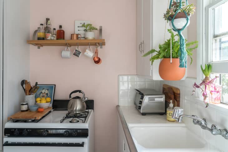 Small studio apartment kitchen with blush pink walls and white cabinets