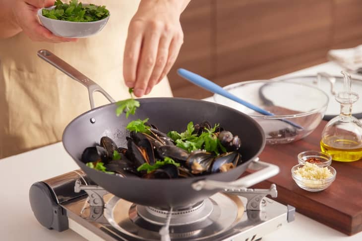Someone using Misen cookware to make steamed mussels.