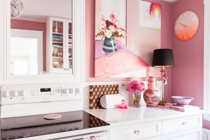 a pink-walled kitchen with white cabinets and pink accents