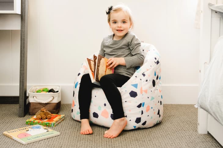 Child sitting in a Big Joe Milano Kid’s Chair in Terrazo pattern. Some books around