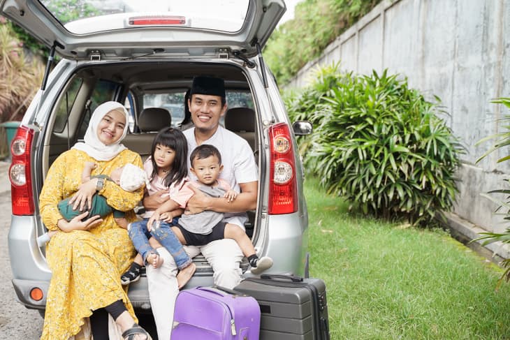 Family sitting by car, ready to go on road trip