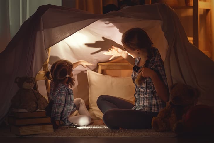 mother and daughter in fort playing shadow puppets