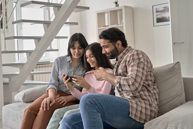 family looking at phone on couch together