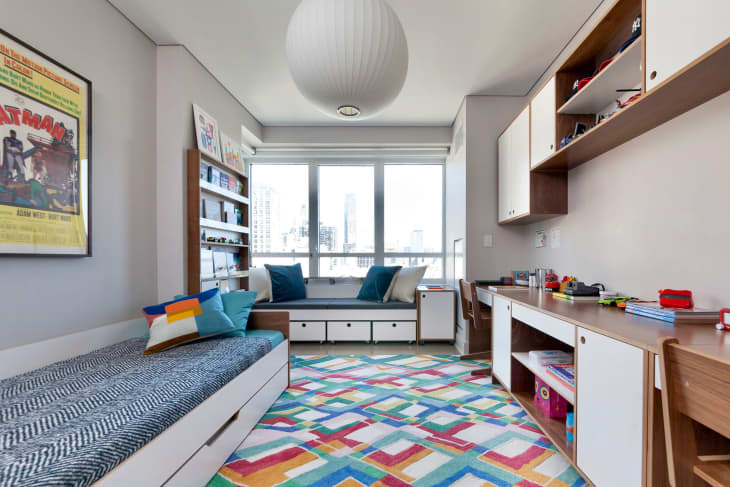 Colorful multipurpose room with paper pendent in the center and lots of storage under bed and sofa.