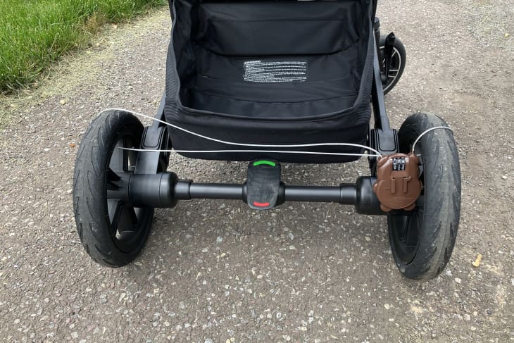 black baby stroller on path that has been locked by simple bike/stroller lock