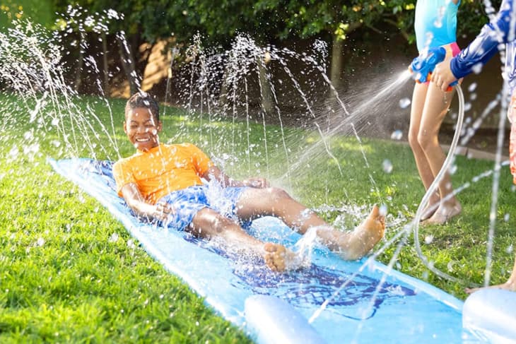 Product photo of NERF Super Soaker Blast Water Slide: shows kids playing with the blaster and slide in a backyard