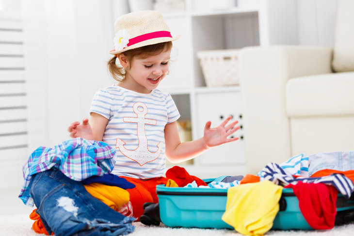 child surrounded by clothing while she packs