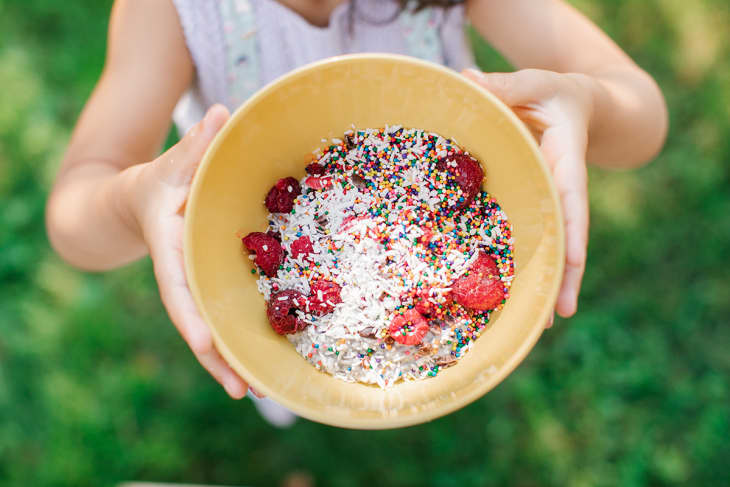 A bowl of chia pudding topped with raspberries, coconut flakes, and colorful sprinkles.