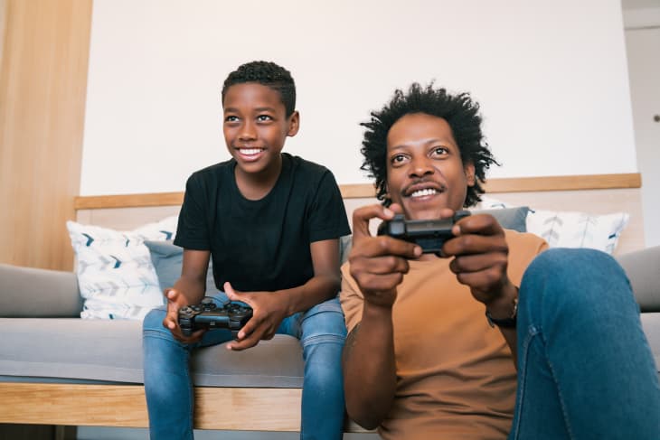 father and son playing video games with smiling faces