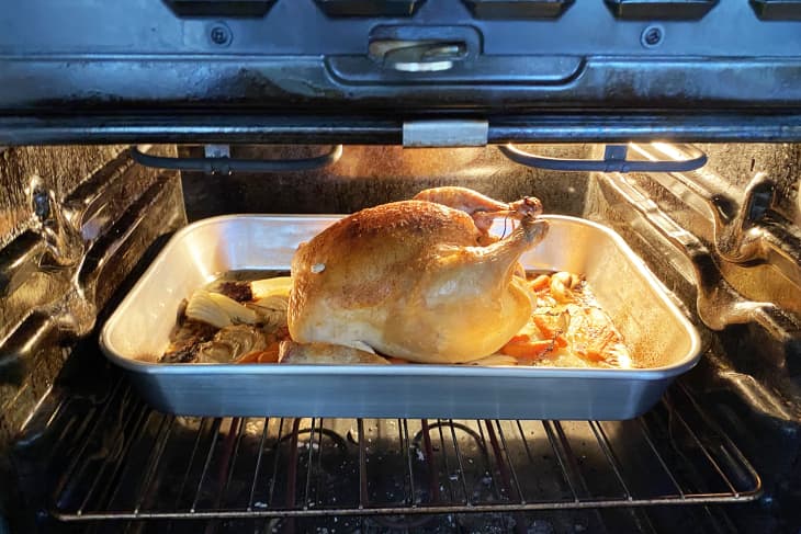 Roast chicken in a baking tray with vegetables inside an oven.