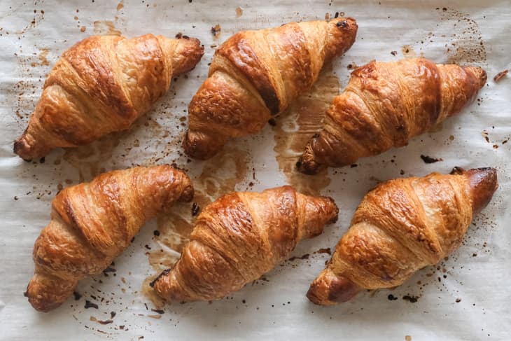 Flaky golden croissants resting on a parchment baking sheet