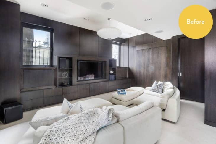 Modern living room with dark wood paneling, white sofas, and a large TV.