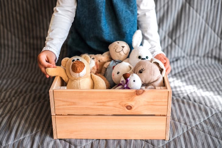 child holding a crate full of stuffed animals